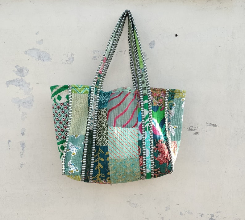 May include: A patchwork tote bag with green, blue, and pink fabric squares. The bag has long straps and a zipper closure.