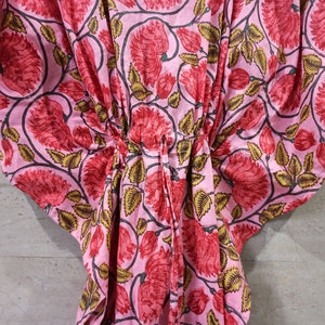 May include: Pink cotton kaftan with a floral print featuring red flowers and green leaves.