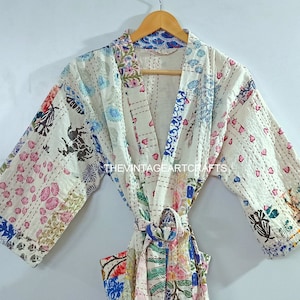 May include: A white cotton robe with a patchwork design featuring floral and geometric patterns in shades of blue, pink, and green. The robe has a tie belt and long sleeves.