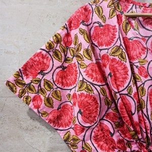 May include: Pink cotton kimono with a floral print featuring red flowers and green leaves.