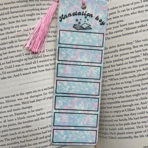 May include: A pink and blue tie-dye bookmark with a black border and the text "Annotation Key" in black. The bookmark has a black and white illustration of a book with stars above it.