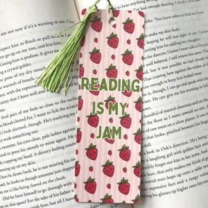 Puede incluir: Un marcapáginas rosa y verde con un patrón de fresas y el texto "Reading is my jam".