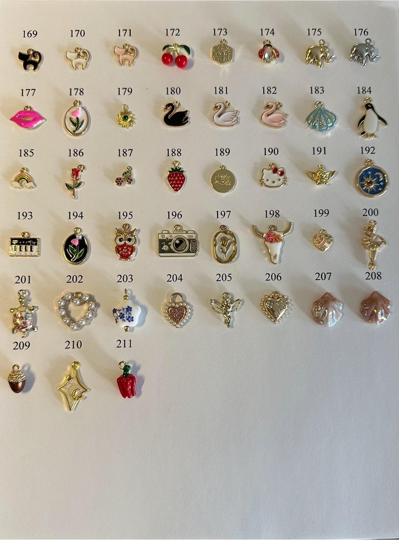 May include: Assortment of 211 colorful enamel charms, including animals, food, and other cute designs. The charms are arranged in rows on a white background.
