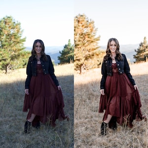 May include: A woman wearing a burgundy dress with a black denim jacket and black boots stands in a field. The dress has a lace bodice and tiered skirt. The background features trees and mountains under a clear sky.