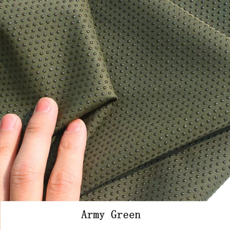May include: Close-up of a green fabric with a textured surface. The fabric has a pattern of small, raised dots.