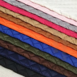 Peut inclure: Présentation diagonale d'échantillons de tissus matelassés de différentes couleurs. Les échantillons comprennent du blanc, rose, gris, rouge, beige, orange, bleu, vert, marron et noir. Chaque tissu présente un motif en losange.