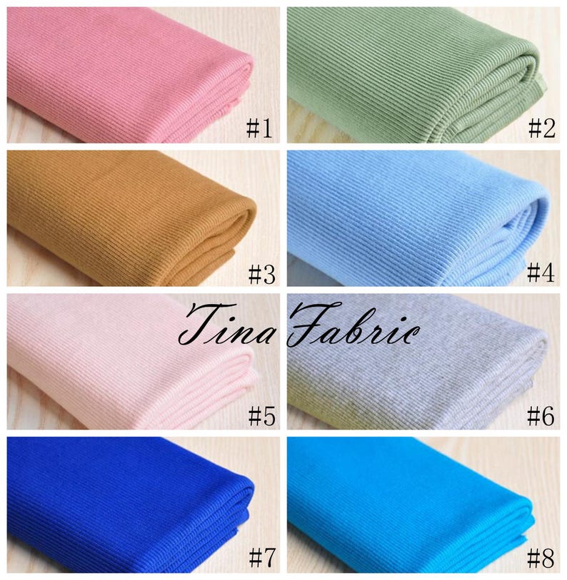 May include: Eight different colours of ribbed knit fabric, folded and displayed on a wooden surface. The colours are pink, green, brown, light blue, light pink, grey, blue, and turquoise.