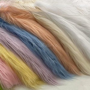 Puede incluir: Muestras de tela de piel sintética en varios colores pastel, como rosa, amarillo, lavanda, azul, melocotón y blanco. La tela tiene fibras largas y suaves, y la imagen está en ángulo para mostrar los diferentes colores. El texto "TinaFabric" es visible.