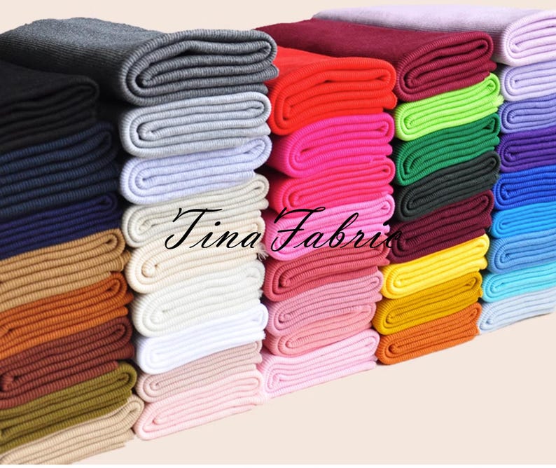 May include: A stack of colourful knit fabric rolls, each roll is a different colour, including red, pink, green, blue, yellow, and white. The rolls are stacked in a neat pile, with the ends of the fabric visible. The fabric is a soft, stretchy knit material that is perfect for sewing projects.