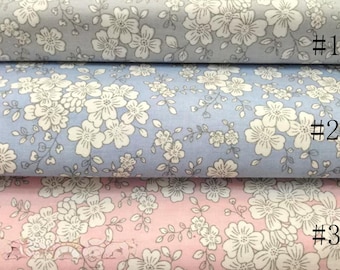 May include: Three rolls of floral fabric in shades of blue and pink. The fabric features a repeating pattern of white flowers and green leaves. The rolls are labeled with numbers 1, 2, and 3.