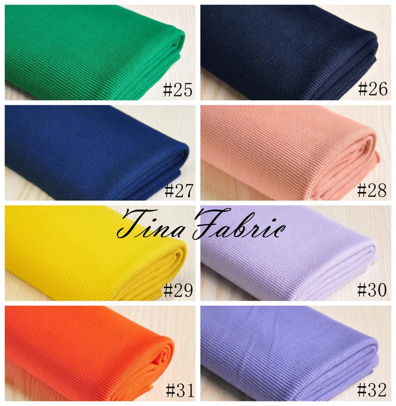 May include: A collection of ten fabric swatches in various colours, including green, blue, pink, yellow, orange, and purple. Each swatch is folded and labelled with a number from 25 to 32. The fabric appears to be ribbed.