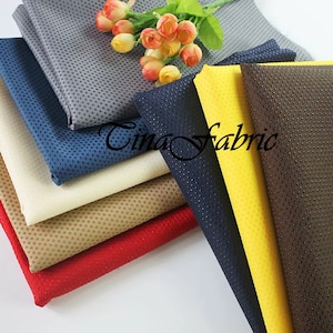 May include: A stack of eight different colored fabrics with a dotted texture. The fabrics are arranged in a fan shape with the top fabric being gray. The text "Tina Fabric" is visible in the center of the image.