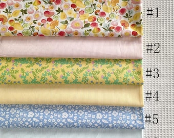 May include: A selection of six fabric swatches. The top swatch features a floral pattern with lemons, flowers, and fruit. The other swatches are solid pink, yellow with green floral, solid yellow, blue floral, and light blue. Each swatch is labeled with a number.
