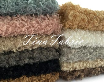 May include: A stack of faux fur fabric in various colors, including light blue, pink, beige, gray, black, and brown. The fabric has a curly texture and is perfect for crafting projects.