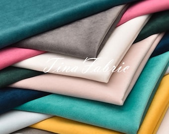 May include: A collection of folded velvet fabric samples in various colors, including teal, gray, pink, white, and yellow. The fabric is soft and appears to have a slight sheen. The text "Tina Fabric" is displayed in a cursive font.