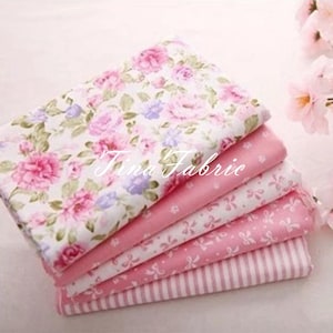 Op de afbeelding: Een stapel van zes roze stoffen vierkanten met verschillende patronen. Het bovenste vierkant heeft een bloemenprint met roze en witte rozen. De andere vierkanten hebben roze en witte stippen, roze en witte strikken en roze en witte strepen.
