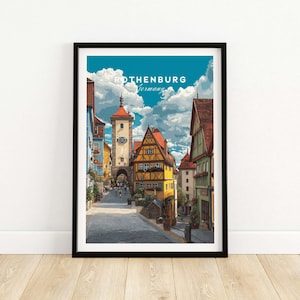 Könnte beinhalten: Ein gerahmter Kunstdruck mit einer farbenfrohen Illustration von Rothenburg, Deutschland. Das Kunstwerk zeigt eine Kopfsteinpflasterstraße mit historischen Gebäuden, einem Uhrturm und einem strahlend blauen Himmel mit Wolken. Der Text "Rothenburg Germany" steht oben.