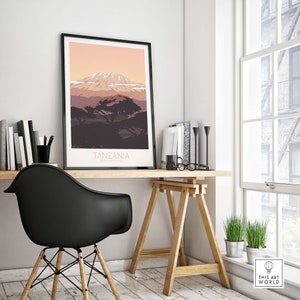 Puede incluir: Una impresi&oacute;n enmarcada en negro con una ilustraci&oacute;n minimalista del monte Kilimanjaro en Tanzania. La impresi&oacute;n tiene un cielo de puesta de sol rosa y naranja con un &aacute;rbol verde oscuro en primer plano. El texto "TANZANIA" est&aacute; impreso en blanco en la parte inferior de la impresi&oacute;n.