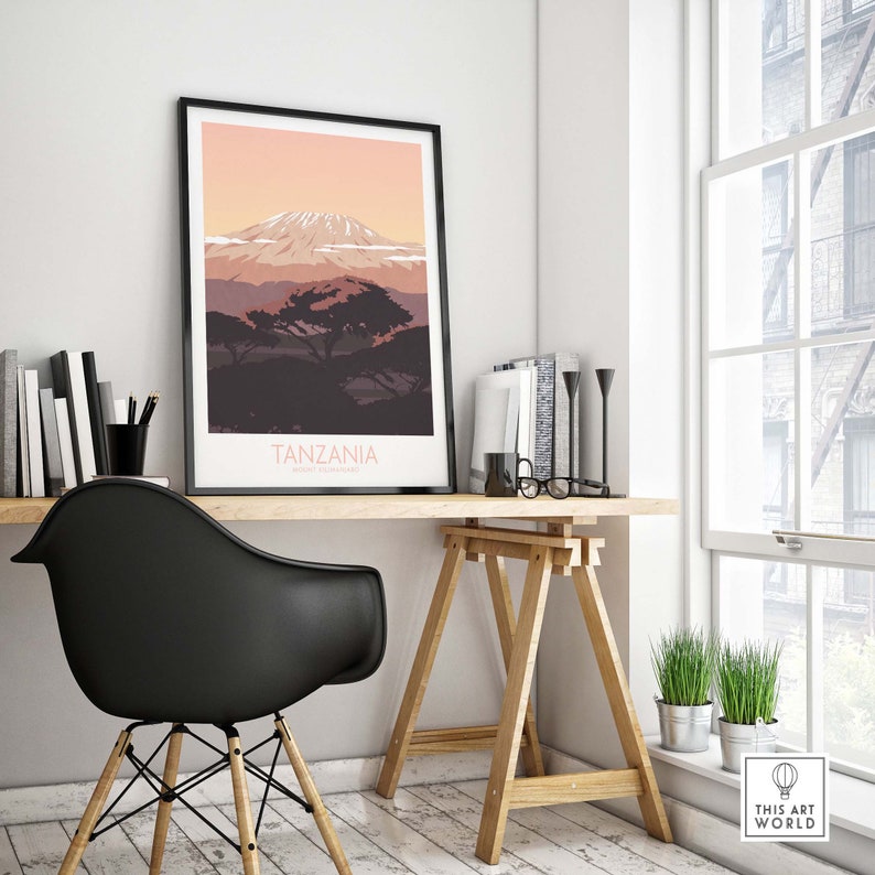 Puede incluir: Una impresi&oacute;n enmarcada en negro con una ilustraci&oacute;n minimalista del monte Kilimanjaro en Tanzania. La impresi&oacute;n tiene un cielo de puesta de sol rosa y naranja con un &aacute;rbol verde oscuro en primer plano. El texto "TANZANIA" est&aacute; impreso en blanco en la parte inferior de la impresi&oacute;n.