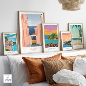 Pode incluir: Cinco posters de viagem emoldurados com ilustra&ccedil;&otilde;es coloridas de diferentes destinos. Os posters est&atilde;o dispostos numa prateleira acima de uma cama branca com almofadas castanhas. Os posters apresentam os seguintes destinos: Costa Amalfitana, Lisboa, Lago Como, San Juan e Maui.