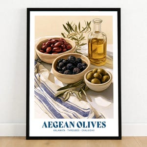 May include: A framed art print titled AEGEAN OLIVES featuring three ceramic bowls filled with Kalamata, Throubes, and Chalkidiki olives, a glass bottle of golden olive oil, and olive branches resting on a white cloth with blue stripes.