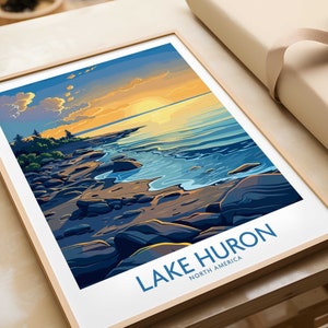 Può includere: Un'illustrazione incorniciata di una costa rocciosa con un lago blu sullo sfondo. Il cielo è di un arancione e giallo vibrante, con nuvole nel cielo. Il testo "LAKE HURON NORTH AMERICA" è stampato nella parte inferiore dell'illustrazione.