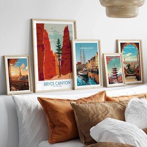 Travel and national park art prints in natural wood frames above a bed with decorative pillows