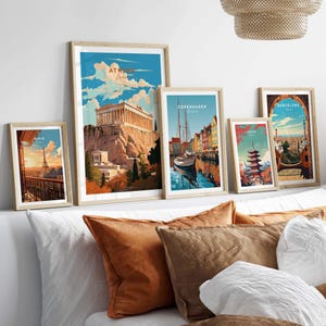 Collection of vibrant city posters featuring Athens, Copenhagen, and Barcelona above a cozy sofa with decorative pillows.