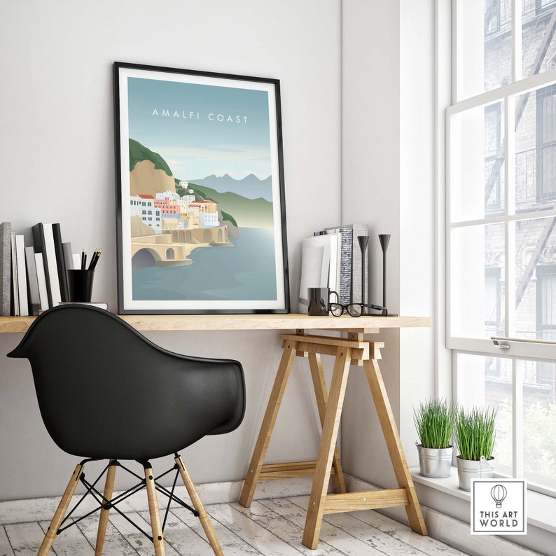 May include: A framed illustration of the Amalfi Coast in Italy. The illustration features a colorful cityscape with a bridge and a blue sea. The text "Amalfi Coast" is printed in white at the top of the illustration.