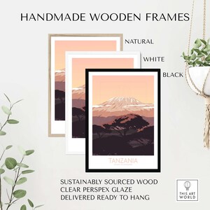 Puede incluir: Una impresi&oacute;n enmarcada de un paisaje de monta&ntilde;a con un cielo rosa y un &aacute;rbol verde oscuro en primer plano. El marco est&aacute; disponible en madera natural, blanco o negro.