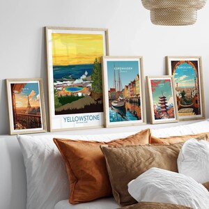 Framed travel posters of Yellowstone, Paris, Copenhagen, Tokyo, Barcelona above a bed