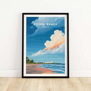Könnte beinhalten: Gerahmter Kunstdruck von Cocoa Beach, Florida, mit einer Strandlandschaft und einem Raketenstart. Das Kunstwerk zeigt einen blauen Himmel mit Wolken, einen Sandstrand und das Meer. Der Text "Cocoa Beach Florida" ist oben abgebildet.