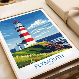 Puede incluir: Una ilustración enmarcada de un faro de rayas rojas y blancas en un acantilado verde con vistas a un mar azul. El texto "PLYMOUTH DEVON" está impreso debajo del faro.