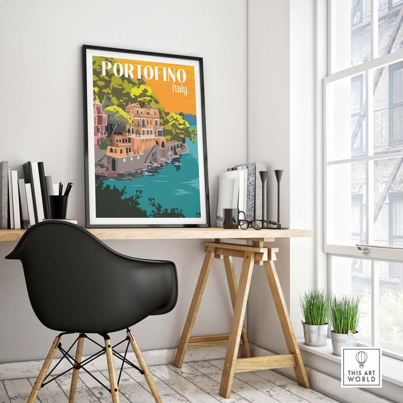 Op de afbeelding: Een zwart ingelijste poster met een kleurrijke illustratie van een kustplaats met gebouwen en een blauwe watermassa. De poster heeft de tekst "PORTOFINO Itali&euml;" in wit.