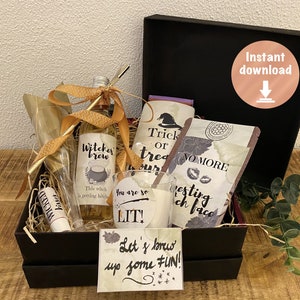May include: A black gift box filled with Halloween-themed items, including a bottle of "Witches Brew", a glass with the text "You are so LIT!" and a bag of coffee with the text "No More" and "Westing Witch Face". The box is decorated with a gold ribbon and a tag that says "Let's brew up some FUN!"