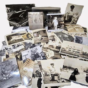 May include: A collection of vintage black and white photographs, depicting various scenes and people. The images include portraits, landscapes, and snapshots of everyday life, offering a glimpse into the past. The photographs are arranged in a pile, showcasing a variety of sizes and subjects.