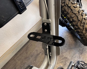 May include: A black metal bike rack mounted to the frame of a silver bicycle. The rack has two holes and the text "4-4" printed on it.