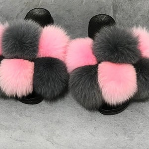 May include: A pair of fluffy slides with a checkerboard pattern of pink and gray fur pom-poms.