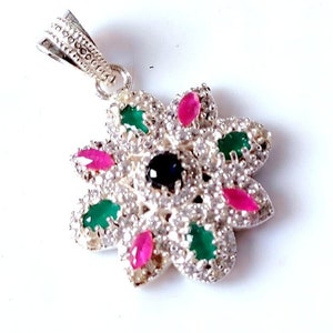 May include: Silver pendant with a flower design featuring clear, pink, and green gemstones. The centre of the flower has a black gemstone.