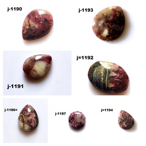 Puede incluir: Seis piedras preciosas talladas en cabujón con diferentes tonos de rosa, blanco y marrón. Las piedras están etiquetadas con los siguientes números: j-1190, j-1193, j-1191, j=1192, j-1186=, j=1194, j-1187.