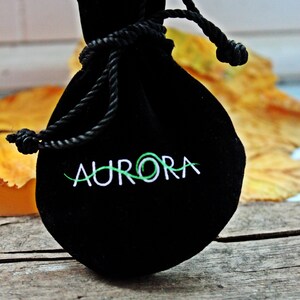 May include: A black velvet drawstring bag with the word "AURORA" embroidered in white on the front.