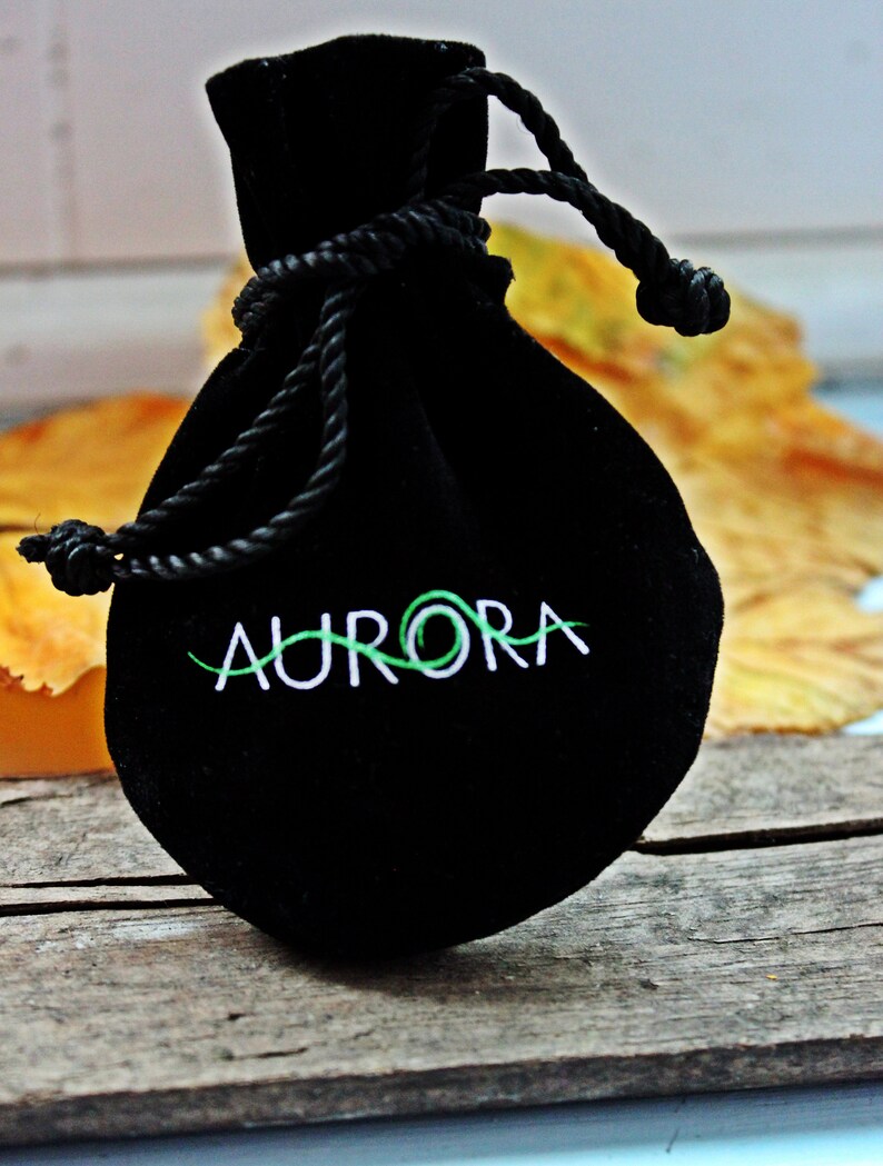 May include: A black velvet drawstring bag with the word "AURORA" embroidered in white on the front.