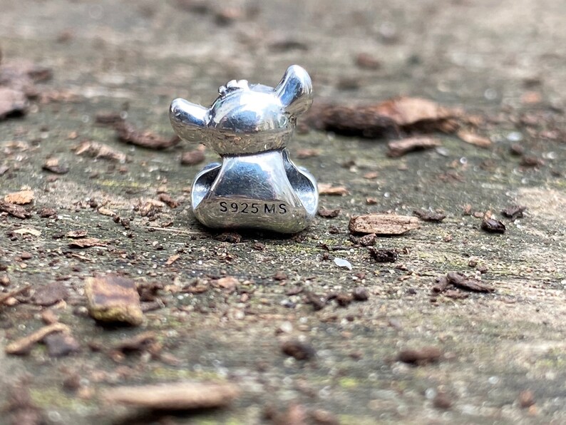 May include: Silver charm featuring a cartoon character with large ears and a wide smile. The charm is marked with the text "S925 MS".