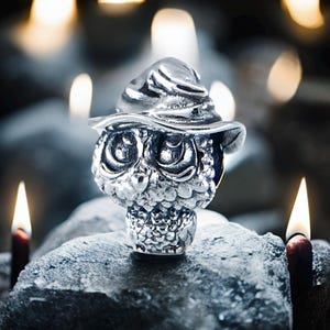 Op de afbeelding: Een zilveren uilbedel met een puntige hoed, de uil heeft grote ogen en een gedetailleerd, getextureerd oppervlak.