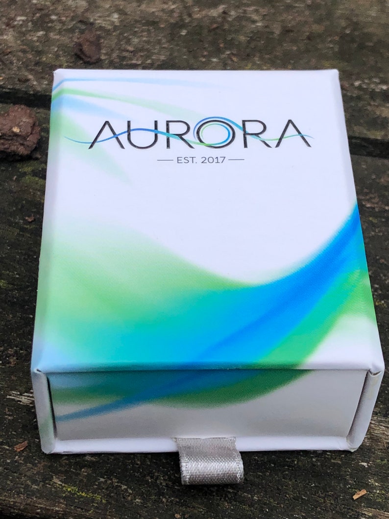 May include: White box with a blue and green abstract design. The box has the text "AURORA - EST. 2017 -" printed on the front.