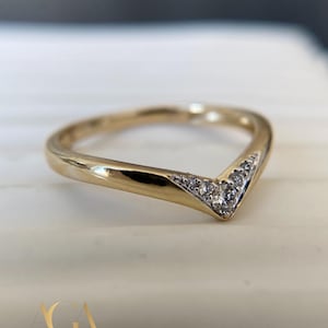 May include: A gold-coloured chevron ring featuring a row of small, clear gemstones set into the V-shape. The ring is on a white surface. The brand name "AffanGemsArt" is at the bottom.