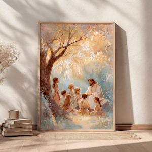 May include: A framed print depicts a religious scene with a man in white robes teaching a group of children under a tree. The artwork features soft colors, with a focus on the figures and the natural setting. The frame is a light wood color.