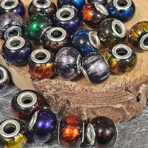 May include: A collection of colorful glass beads with silver accents. The beads are round and have a variety of patterns and textures. They are perfect for jewelry making or other craft projects.