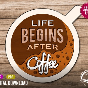 Puede incluir: Una taza de café marrón y blanca con el texto "Life Begins After Coffee" en blanco. La taza está sobre un fondo de madera.