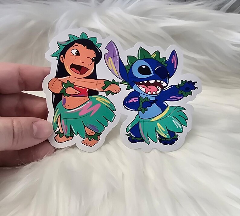 Puede incluir: Dos pegatinas coloridas con Lilo y Stitch de la pel&iacute;cula de Disney Lilo & Stitch. Lilo lleva una falda de hierba verde con detalles rosas y azules. Stitch lleva una falda de hierba azul con detalles verdes y amarillos. Ambos personajes est&aacute;n bailando.